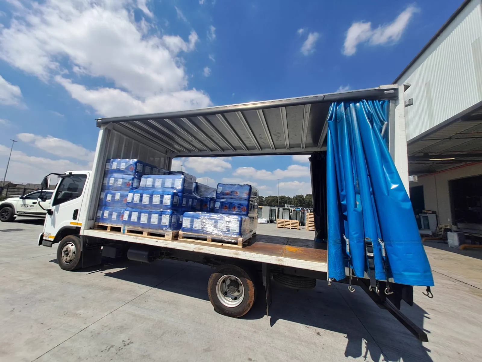 MDL Logistics curtain-side truck with the curtain open, loaded with wrapped pallets at a warehouse